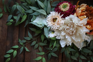 Floral arrangement with white, pink, and orange flowers on a wooden background