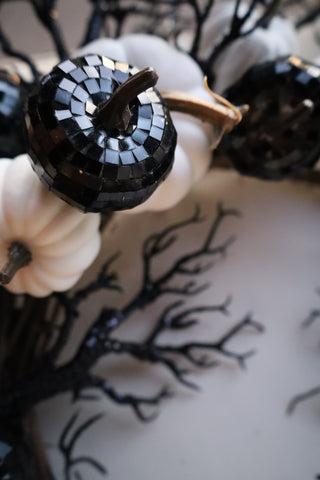 Decorative black and white mosaic pumpkin with tree silhouette in the background