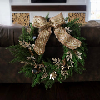 Decorative wreath with a gold bow on a couch in a living room setting.