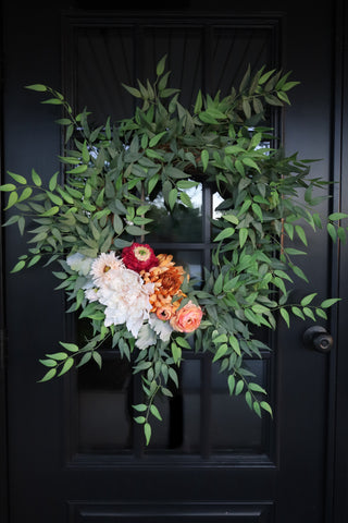 Floral wreath with green leaves and colorful flowers on a black door