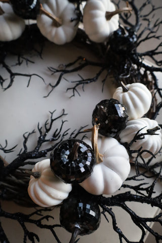 Decorative wreath with white pumpkins and black berries on a white background